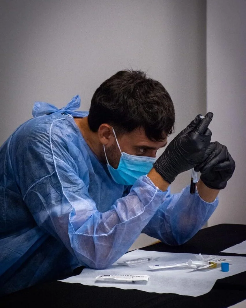 Bioquímico de AV con equipo de protección personal sosteniendo un tubo con la muestra